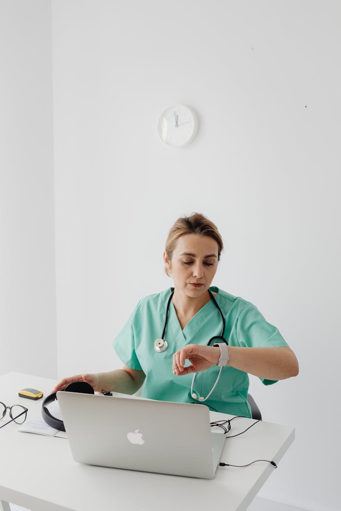 A female doctor checks the time during an online consultation at her desk.